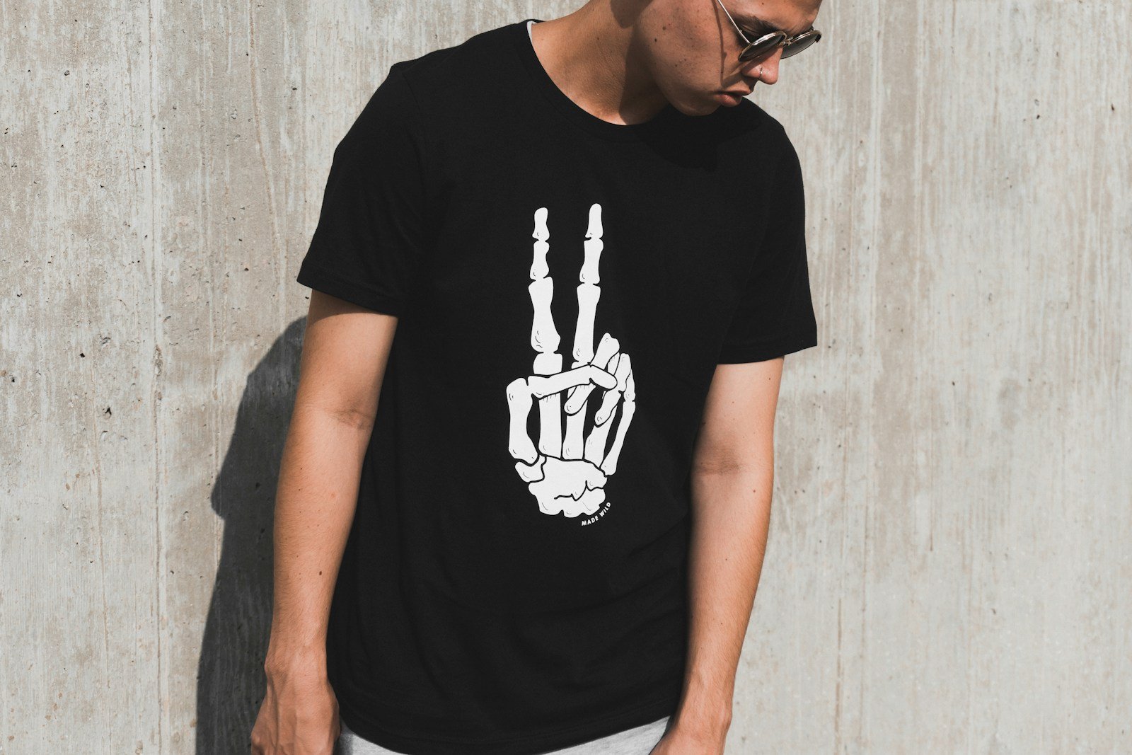 man wearing black shirt and sunglasses leaning against the wall during daytime
